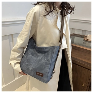 Detail view of denim canvas crossbody bag with multi-pocket design and leather fashion label