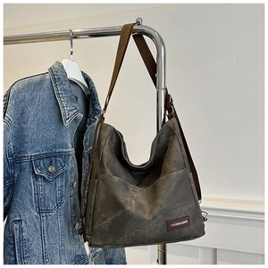 Detail of grey vintage textured handbag featuring a woven strap and FASHION & BAGS patch