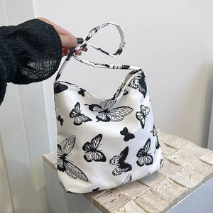 Detail der weißen Canvas-Tasche mit schwarzem Schmetterlingsdruck auf Steinsockel