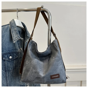 Close-up of retro grey canvas hobo bag with adjustable brown strap and fashion label