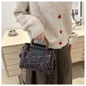 Close-up of leopard print handbag featuring a vintage semicircular wooden handle and leather strap