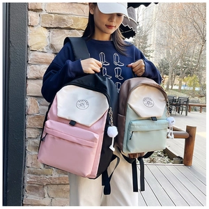 Detalle de mochilas de nylon bicolor en rosa y verde con colgantes de felpa suave
