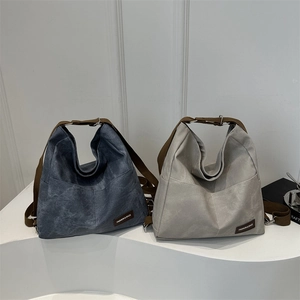 Minimalist large hobo backpacks in navy and grey with brown fabric straps on a stand