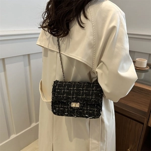 Primer plano de bolso bandolera de tweed blanco y negro con cadena dorada en modelo