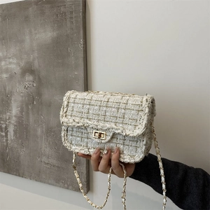 Detail of tweed texture and golden metal twist-lock on a stylish crossbody bag