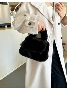 Détail d'un sac à main noir en peluche avec une chaîne en perles blanches sur un modèle