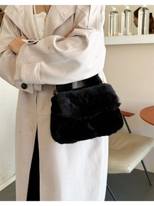 Détail d'un sac bandoulière en peluche noire avec des accents de chaîne dorée chic