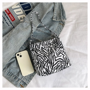 Detail der Zebra-Einkaufstasche mit Schultergurt neben einem weißen Smartphone gezeigt