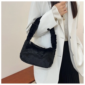 Detail of soft black plush shoulder bag with silver zipper on white blazer outfit
