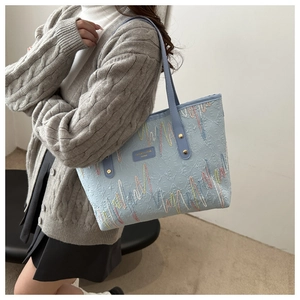 Detalle del bolso tote azul claro con bordado ondulado de colores y textura en relieve