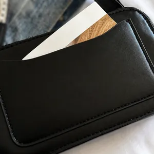 Detailopname van zwarte leren tas met functionele kaartsleuf aan voorzijde en strak stikwerk