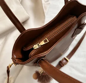 Detailed close-up of smooth gold-tone zipper and fine stitching on brown leather bag