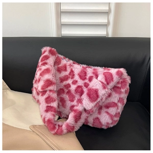 Detail of pink leopard print faux fur plush shoulder bag with wide handle on leather sofa