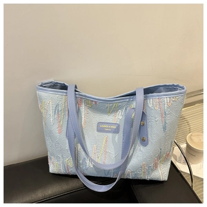 Detalle del bolso tote azul claro con relieve de letras 3D y bordado ondulado elegante