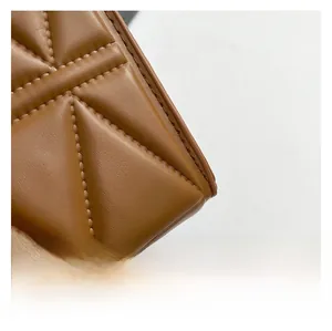 Detailed close-up of brown quilted faux leather texture with neat stitching on handbag