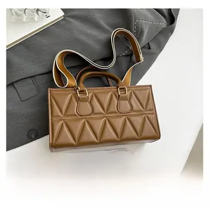 Detail view of brown quilted bag with woven strap and smartphone for size comparison