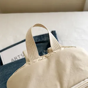 Detail of reinforced woven handle and textured fabric on minimalist beige commuter backpack