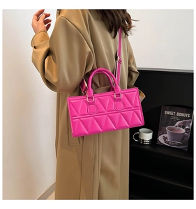 Detail of fuchsia quilted handbag featuring geometric patterns and a stylish wide strap