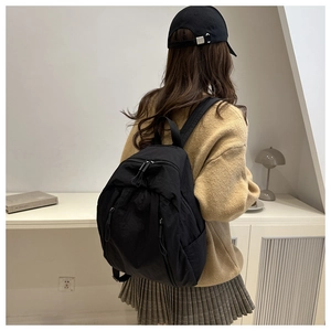 Detail of a black minimalist nylon backpack showing double-zipper pockets and durable texture