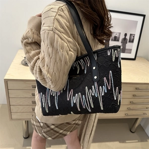 Bolso tote negro con bordados de ondas coloridas y correas de cuero elegantes