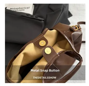 Detail view of the brown leather bag's internal gold magnetic snaps and fabric lining