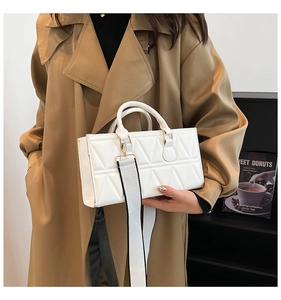 White quilted handbag with geometric pattern and wide canvas strap worn with a trench coat