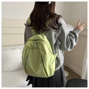 Detailed side view of light green nylon backpack featuring vertical zipper pockets and lightweight design