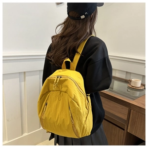 Detail view of bright yellow nylon backpack with multi-zipper pockets and durable handles
