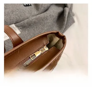 Gros plan d'une fermeture éclair dorée et d'un cuir tressé sur un sac marron