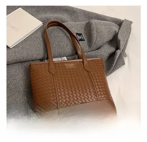 Détail du sac cabas marron en cuir tressé avec marquage doré sur un manteau en laine