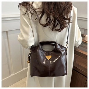 Deep brown oily leather bucket bag with gold triangle logo and vintage bell charm details