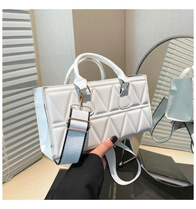 Close-up of white quilted crossbody bag featuring triangular patterns and gold hardware