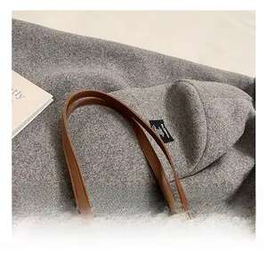 Détail du cabas en cuir tressé marron avec poignées lisses et logo doré gravé