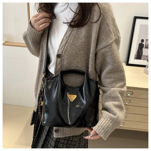 Detail of black glossy bucket bag with golden triangle logo and fine stitching
