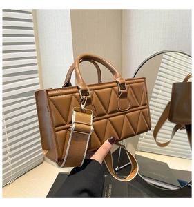 Close-up of caramel winter handbag featuring geometric quilted pattern and wide woven strap