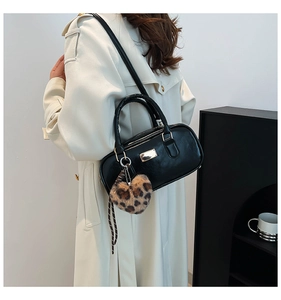 Détail d'un sac bowling en cuir noir avec breloque cœur léopard et garniture dorée