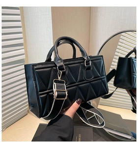 Detail of quilted black crossbody bag featuring triangle patterns and a wide fabric strap