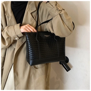 Détail de la texture en cuir tressé et du logo embossé sur ce sac cabas noir élégant