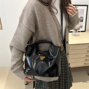 Glossy black leather bucket bag with gold hardware and iconic logo for women