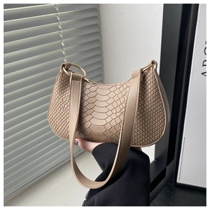 Dettaglio della borsa a mezzaluna beige con trama goffrata e anello in metallo dorato