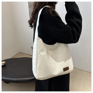 Dettaglio della grande borsa tote bianca con etichetta del marchio marrone a contrasto