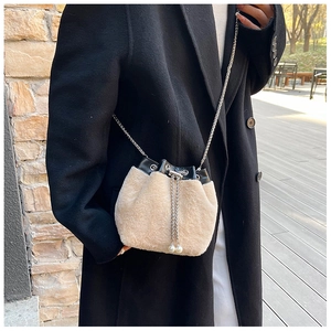 Détail du sac seau en peluche crème avec bordure en cuir noir et chaîne à perles