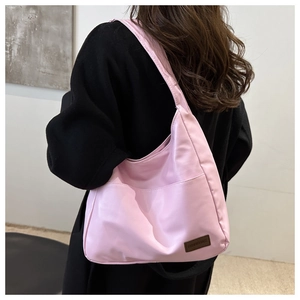 Dettaglio della borsa a tracolla rosa chiaro con tasca esterna ed etichetta in pelle