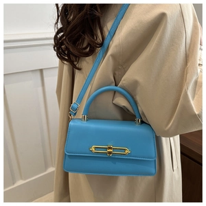 Detail of bright blue leather crossbody bag with elegant gold chain buckle and top handle