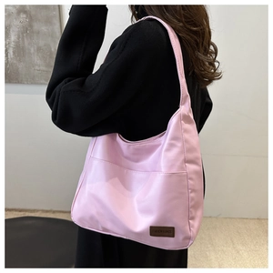 Dettaglio della borsa tote in nylon rosa con etichetta in pelle vista in prospettiva laterale