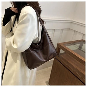 Dettaglio di borsa tote vintage marrone scuro indossata con cappotto di lana beige