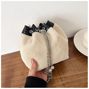 Détail d'un sac seau beige en peluche avec chaîne argentée et pendentif perle élégant
