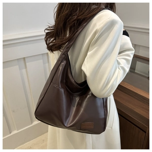 Dettaglio della borsa tote marrone scuro con trama in pelle e tasca laterale su cappotto bianco