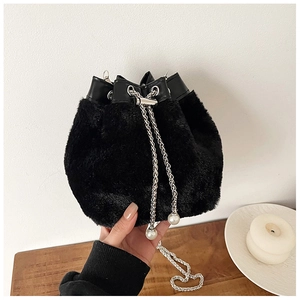 Gros plan du sac seau en fausse fourrure noire avec chaîne argentée et détails perles