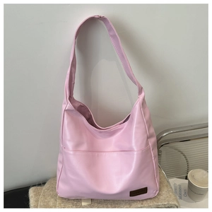 Dettaglio della borsa hobo in pelle PU rosa con patch logo su uno sfondo materico